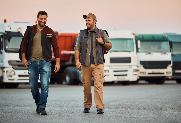 Two men walking in front of semi-trucks